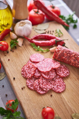 Sliced salami sausage on wooden cutting board at domestic kitchen