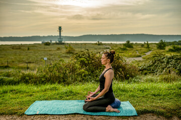 a woman ist practicing yoga at the beach