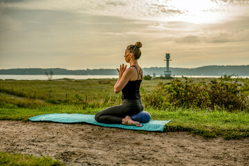 a woman is exercising Yoga at the beach