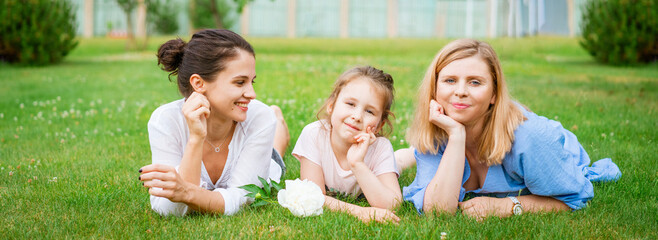 Happy three generation caucasian family lying on grass together in park mother daughter and...