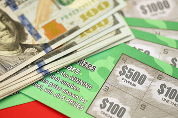 Close up view of green lottery scratch cards and us dollar bills. Many used fake instant lottery tickets with gambling results. Gambling addiction - Powered by Adobe