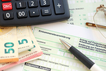 German income tax return form with pen and european euro money bills lies on accountant table close...