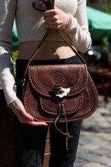 Fototapeta na wymiar small brown women's leather bag with a carved pattern. selective focus