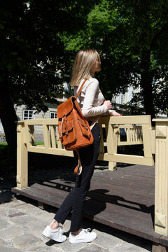 photo of a woman with a orange leather backpack with antique and retro look. Outdoors photo