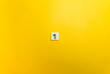 The Pilcrow, ¶, Typographical Character on Letter Tile on Yellow Background. Minimal Aesthetics.