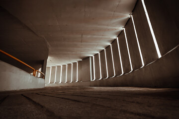 Obraz premium Light channels from cement wall of Curving shaped ramp on high building for indoor car parking lot. Copy space, Selective Focus.