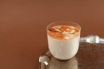 Salep or Sahlep in glass on brown background. Selective focus, copy space. Salep - Turkish instantly drink with cinnamon