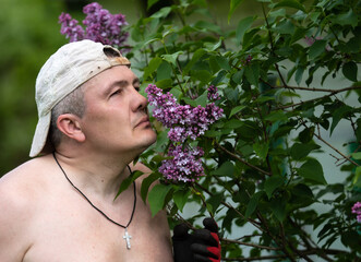 the guy in the cap sniffs lilac