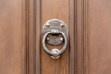 Vintage forged door knocker in the wooden door
