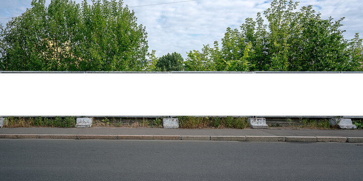 Large empty white advert billboard fixed on concrete fence on sidewalk at city street front view