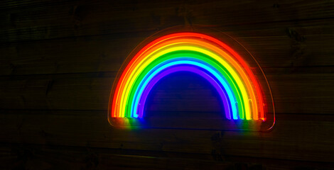 led neon rainbow hanging on the wooden wall