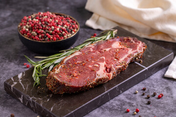 Beef ribeye on a dark background. Fresh raw beef ribeye with spices. close up