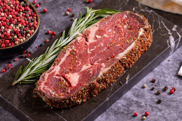 Beef ribeye on a dark background. Fresh raw beef ribeye with spices. close up