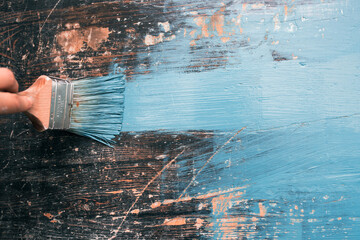 Close up paintbrush in hand and painting on the wooden table.