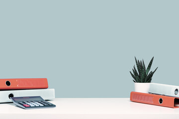 Calculator and orange document binders or lever arch file on an office shelf or desk. Cactus succulent in a pot. Business concept banner. Copy space