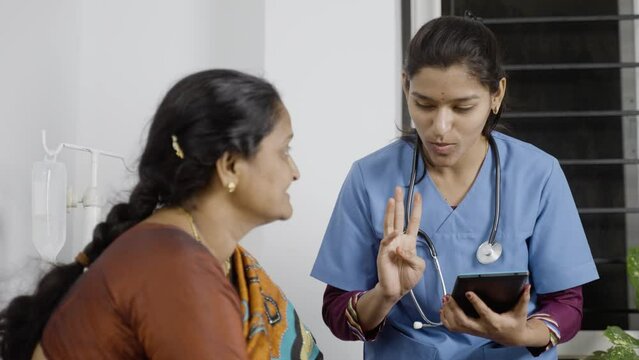 Doctor or nurse advising middle aged woman by seeing report from digital tablet at nursing home - conept of technology, healthcare and medical service