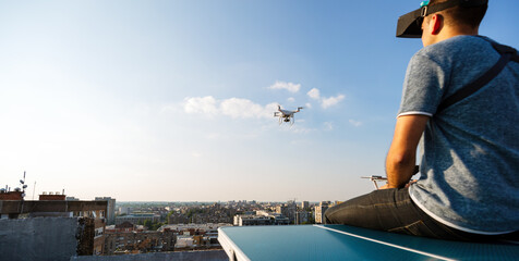 Young technician man flying UAV drone with remote control in city