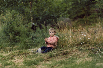 cute little caucasian boy sitting alone on grass