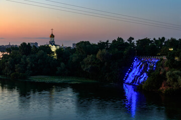 Night view of Monastyrsky Island with illuminated artificial waterfall 