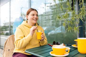 Happy Young woman sitting on the cafe terrace on the modern city street. Person sitting at...