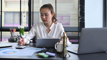 Focused professional accountant is using calculator and preparing annual financial report at office