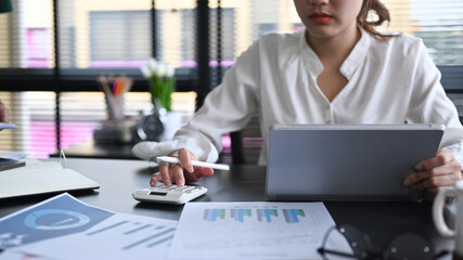 Professional accountant is using calculator and preparing annual financial report at office desk