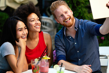 Friends having a great time in cafe, smiling and drinking cocktails enjoying together.