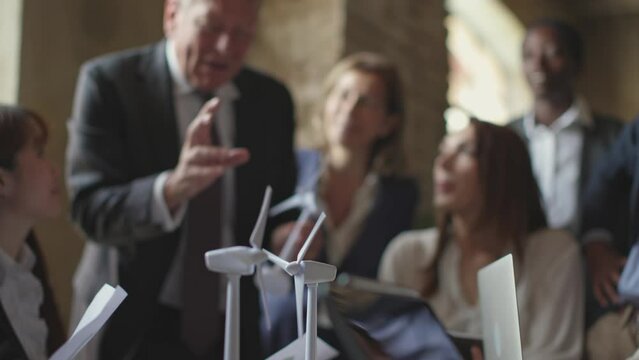 model windmill turbines in motion - people in the background discuss a project