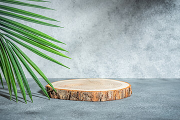 Wooden podium with green palm leaves and shadow. Gray concrete background. Mockup for presentation...