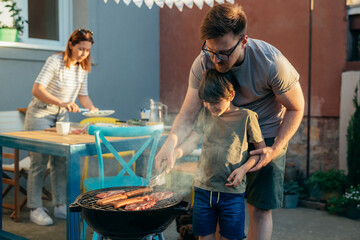 father and son grilling barbecue in backyard - Powered by Adobe