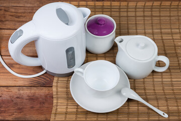 Fototapeta na wymiar Plastic electric kettle and tea utensils on old wooden table
