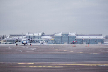The terminal of the international airport in winter in the snow. Apron with civil aircraft in front of the apron.