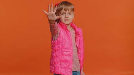 No stop. Serious little girl say no, hold palm folded crossed hands in stop danger gesture, warning of finish prohibited access declining communication, body language. Young child on orange background