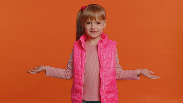 What Why. Sincere Irritated Little Girl Raising Hands In Indignant Expression Asking Reason Of Failure Demonstrating Disbelief Irritation By Troubles. Confused Child Isolated On Orange Wall Background