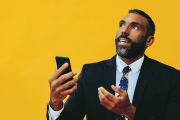 Fototapeta portrait of anxious stressed expressive bearded gentleman in suit and tie with smartphone video call hand up yellow background studio obraz
