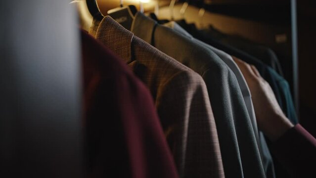 Close up shot of unrecognizable man choosing suit jacket at wardrobe, deciding what to put on in morning before work