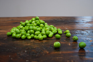 Fresh peeled green pease on a brown wooden table with copy space. Still life of green peas in pods with pea shoots on wooden table