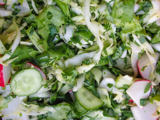 Salad of cucumbers, radishes, onions and herbs. Organic vegan food. Salad texture closeup.