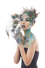 Fantasy portrait of Asian girl with bright creative makeup with peacock feathers isolated on white...