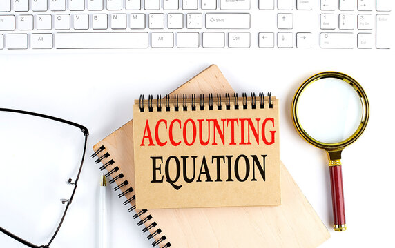 ACCOUNTING EQUATION text in the office notebook with keyboard, magnifier and glasses , business concept