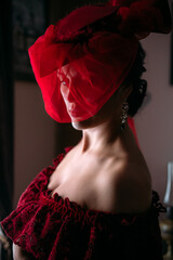 Portrait of beautiful woman in red vintage hat with veil 1800s early 1900s clothing.