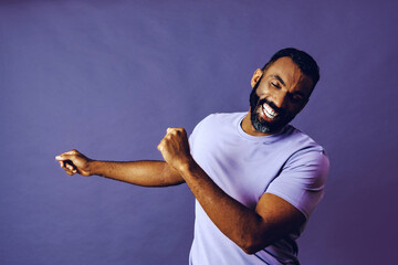 portrait of a successful man dancing with a beard and a blue t-shirt celebrating with arm up on a...