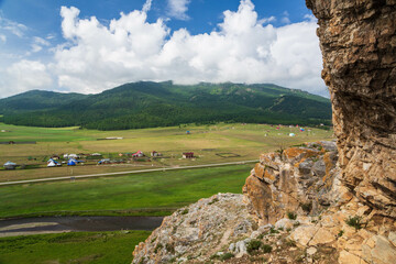 View from the cave in the mountain over the hills, mountains, valley, river and village. Ust-Kansk, Altai region, Siberia, Russia