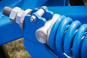 Hard blue spring made of steel. Part of big industrial or agricultural machine