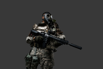 Studio shot of black military man with gas mask holding rifle isolated on grey background.
