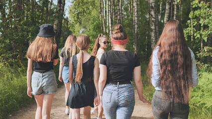 A group of girls are walking by the forest on a summer day.