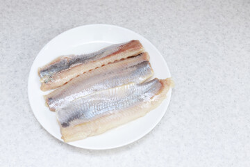 herring fillet on a white plate on the kitchen table