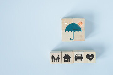 wooden cube block with umbrella with thunder and sun icon on top, insurance concept for health,...