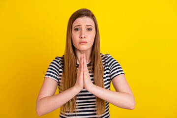 Photo of young woman hands together ask beg pray wish luck wait isolated over yellow color...