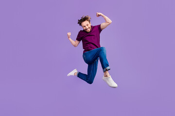 Full length photo of young excited man jumper fists hands awesome isolated over violet color background